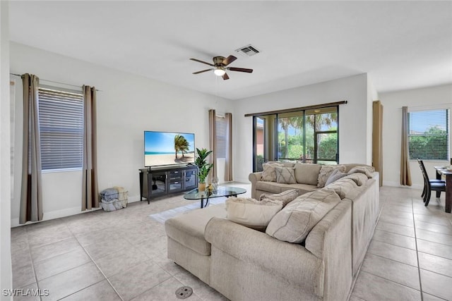 living room with light tile patterned floors, ceiling fan, and baseboards