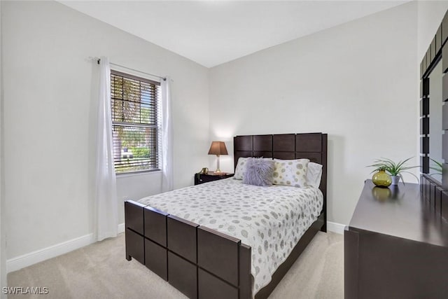 bedroom with light colored carpet and baseboards