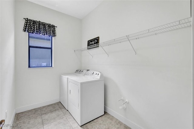 laundry area featuring washer and clothes dryer, baseboards, and light tile patterned floors