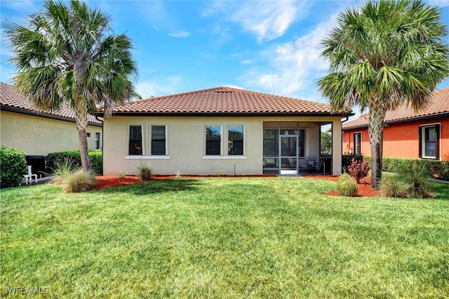 back of property featuring stucco siding, a tiled roof, a yard, and a sunroom