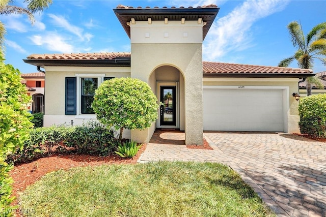 mediterranean / spanish-style house with an attached garage, stucco siding, driveway, and a tile roof