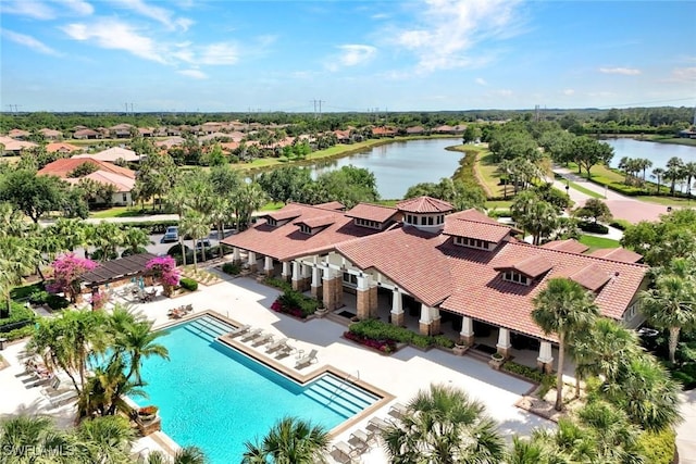 aerial perspective of suburban area featuring a pool and a nearby body of water