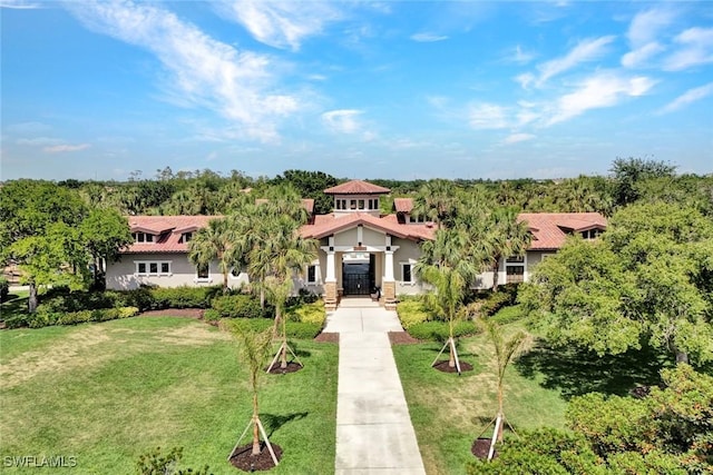 view of front facade with stucco siding, a front lawn, and a tiled roof