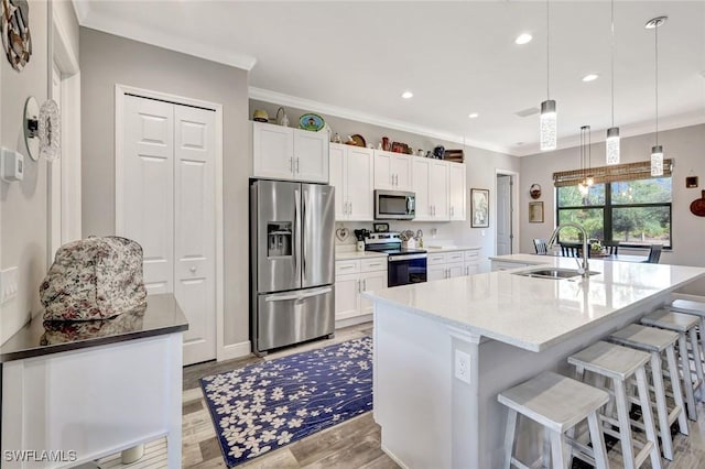 7824 7th Ter, Labelle, FL 33935 - kitchen featuring stainless steel appliances, a sink, ornamental molding, white cabinetry, and light wood finished floors