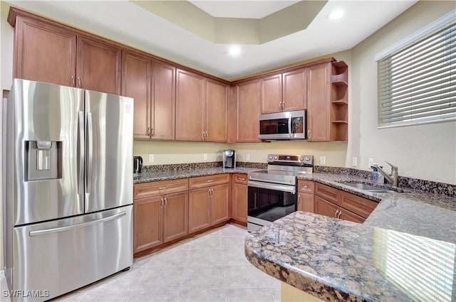 9820 Healthpark Cir Unit 101, Fort Myers, FL 33908 - kitchen with appliances with stainless steel finishes, a sink, open shelves, dark stone countertops, and brown cabinetry