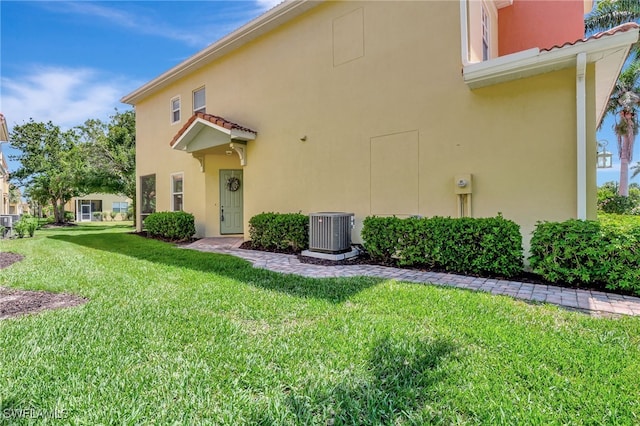 9820 Healthpark Cir Unit 101, Fort Myers, FL 33908 - view of side of home with central AC, stucco siding, and a lawn