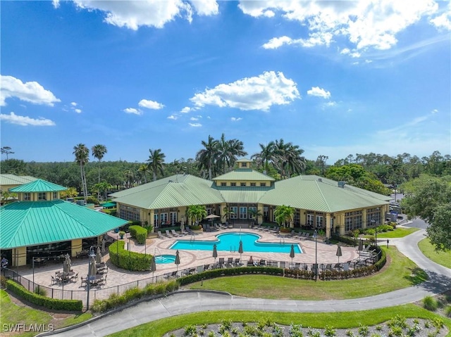 community pool featuring fence, view of wooded area, and a patio