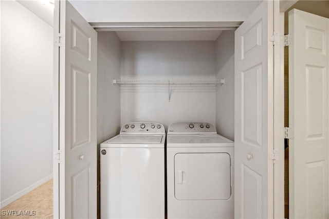 laundry area with independent washer and dryer, light tile patterned floors, and baseboards