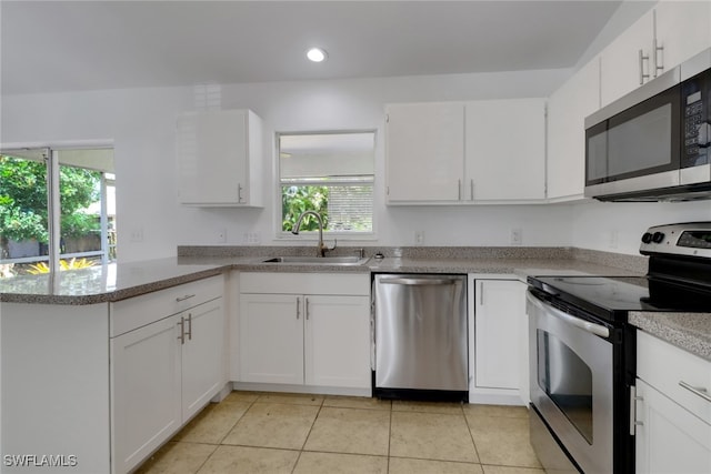 18298 Hepatica Rd, Fort Myers, FL 33967 - kitchen featuring appliances with stainless steel finishes, a sink, light tile patterned flooring, a peninsula, and white cabinetry