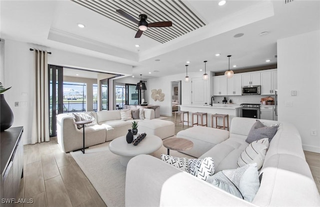12429 Basalt Ln, Alva, FL 33982 - living area with a raised ceiling, a ceiling fan, recessed lighting, light wood-style floors, and baseboards