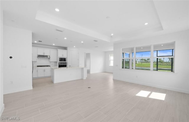 12429 Basalt Ln, Alva, FL 33982 - unfurnished living room featuring a tray ceiling, recessed lighting, and light wood-style flooring