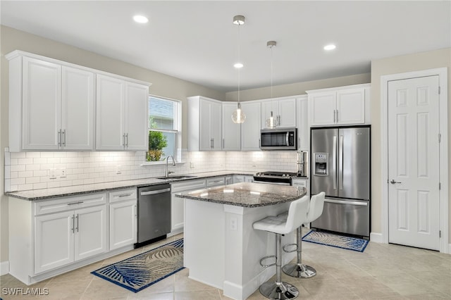 17672 Silverspur Dr, Punta Gorda, FL 33982 - kitchen with appliances with stainless steel finishes, dark stone counters, white cabinets, tasteful backsplash, and a kitchen island