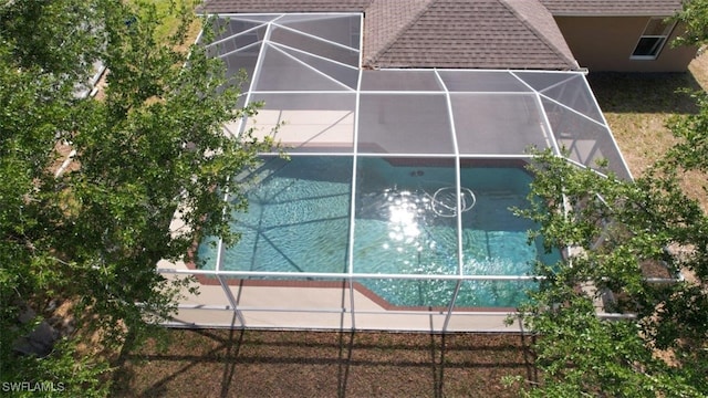 view of property exterior with a shingled roof and glass enclosure