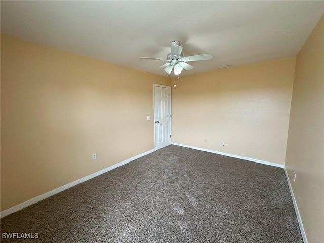 empty room with a ceiling fan, dark colored carpet, and baseboards