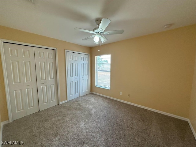 unfurnished bedroom featuring multiple closets, carpet, and baseboards
