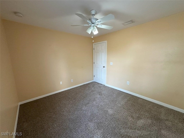 empty room with a ceiling fan, dark colored carpet, and baseboards