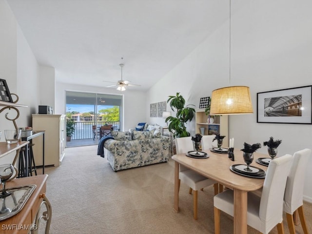 carpeted dining space featuring ceiling fan and high vaulted ceiling