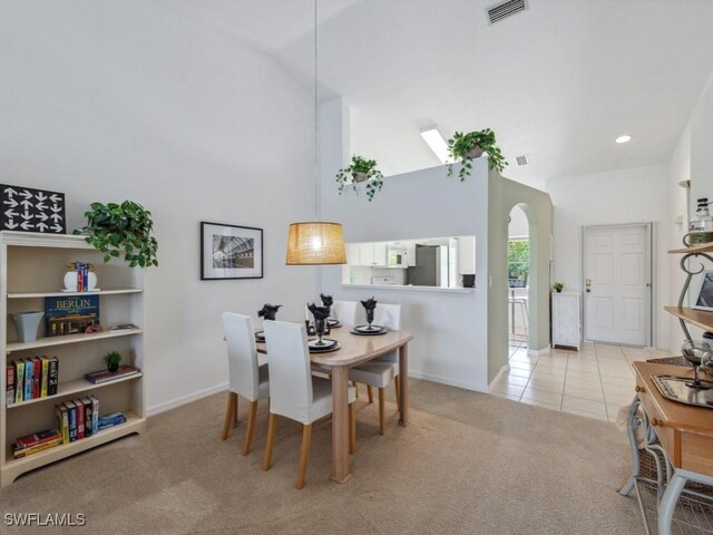 dining room featuring carpet, arched walkways, baseboards, high vaulted ceiling, and tile patterned flooring