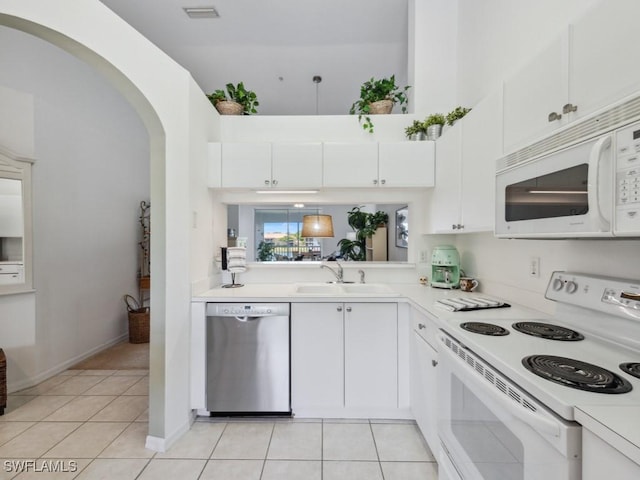 kitchen with white appliances, light countertops, light tile patterned floors, a sink, and white cabinets