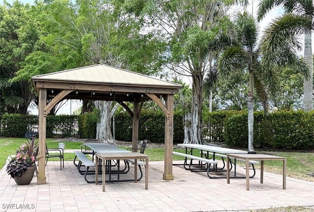 view of community with outdoor dining space, a gazebo, a patio, and a lawn