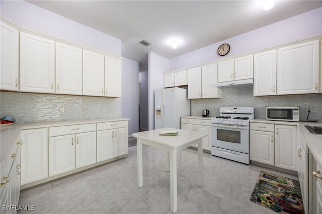1083 Pollywog Dr, Labelle, FL 33935 - kitchen featuring white appliances, under cabinet range hood, tasteful backsplash, light countertops, and light marble finish flooring