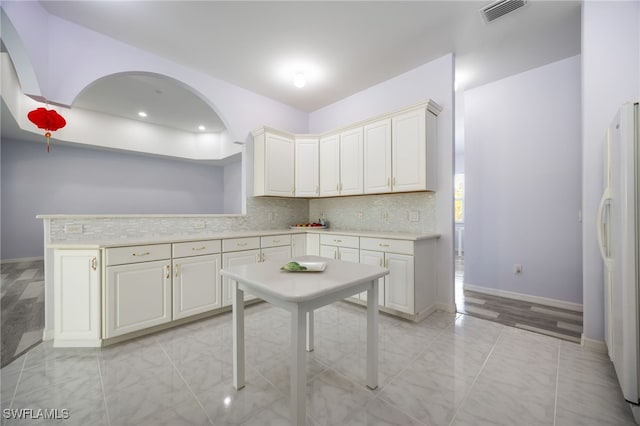 1083 Pollywog Dr, Labelle, FL 33935 - kitchen with freestanding refrigerator, light countertops, backsplash, baseboards, and arched walkways