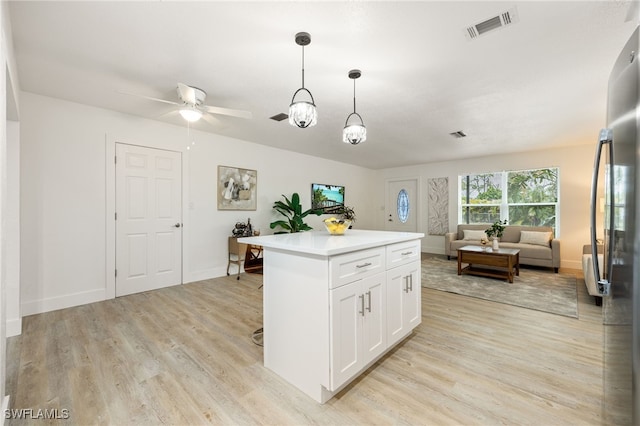 5863 Millay Ct, North Fort Myers, FL 33903 - kitchen featuring freestanding refrigerator, light wood finished floors, open floor plan, white cabinetry, and pendant lighting