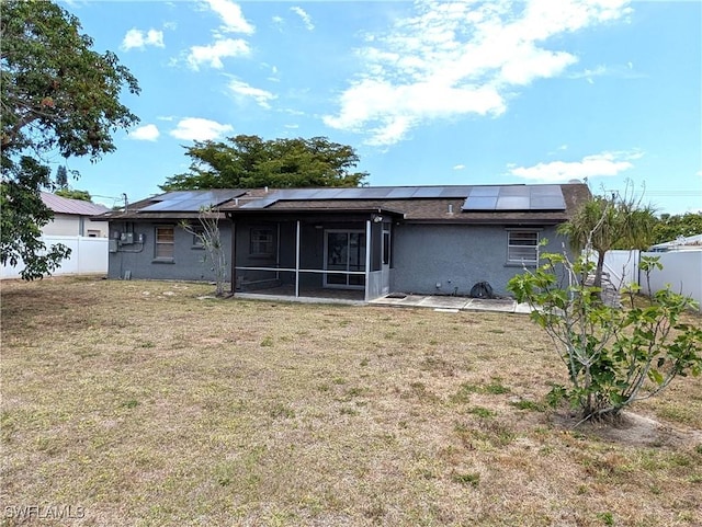 back of property featuring a sunroom, roof mounted solar panels, and stucco siding