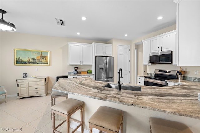 3932 Ruxton Rd, Naples, FL 34116 - kitchen with stainless steel appliances, a sink, light stone counters, a peninsula, and white cabinets
