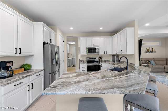 3932 Ruxton Rd, Naples, FL 34116 - kitchen featuring stainless steel appliances, a sink, light tile patterned floors, a peninsula, and light stone countertops