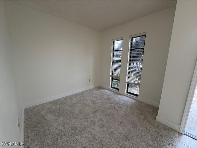 empty room featuring light carpet and baseboards