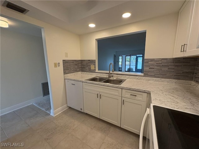 kitchen with a sink, white appliances, backsplash, light countertops, and white cabinetry