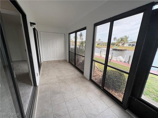 unfurnished sunroom with a water view and tile patterned flooring