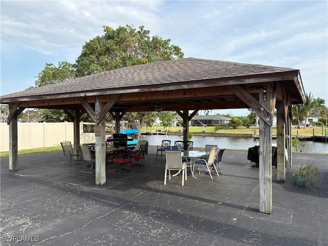 view of home's community featuring a gazebo, fence, a water view, and outdoor dining space