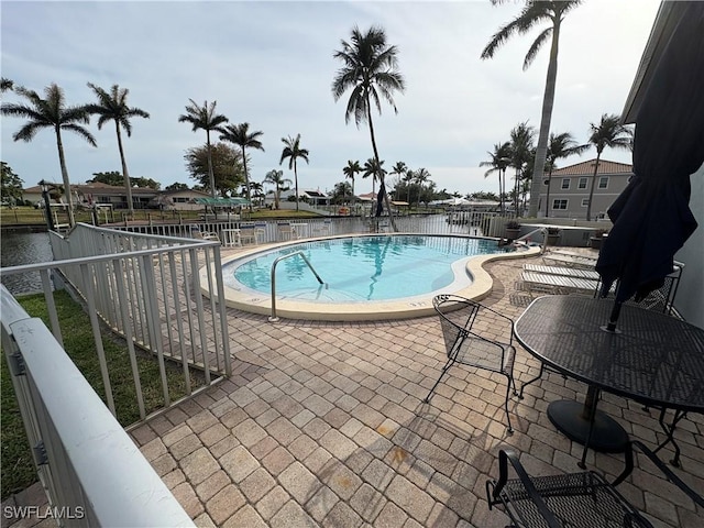 community pool with a patio area and fence