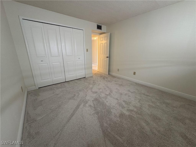 unfurnished bedroom featuring baseboards, carpet floors, a textured ceiling, and a closet