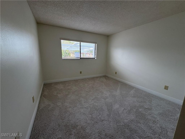 empty room with light carpet, a textured ceiling, and baseboards