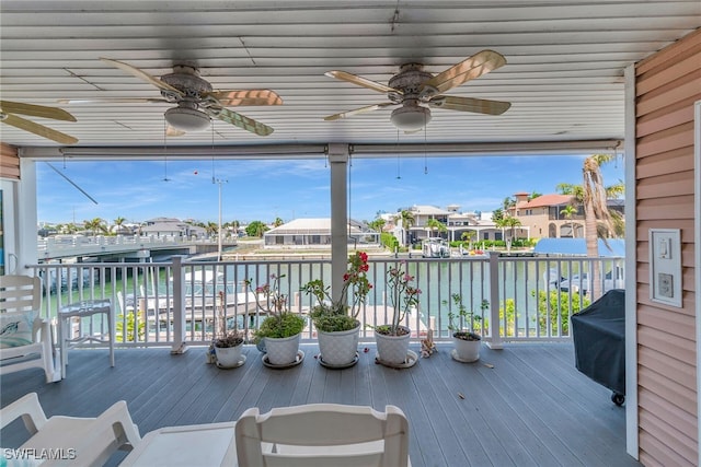 wooden terrace featuring ceiling fan, a water view, and a residential view