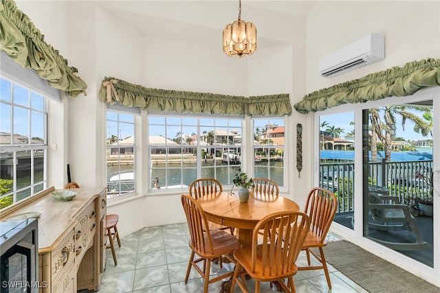sunroom / solarium with an AC wall unit, a chandelier, a water view, and a high ceiling