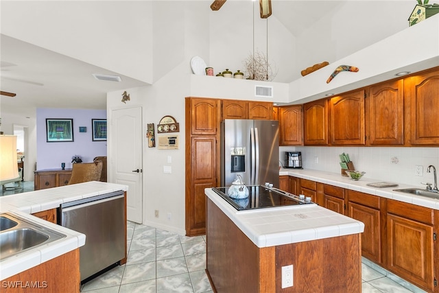 kitchen featuring stainless steel appliances, a ceiling fan, high vaulted ceiling, a center island, and brown cabinets