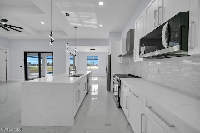 kitchen featuring stainless steel appliances, wall chimney exhaust hood, a sink, recessed lighting, and tasteful backsplash