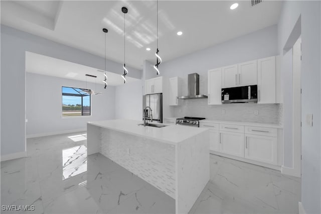 kitchen featuring stainless steel appliances, wall chimney range hood, white cabinetry, a sink, and recessed lighting