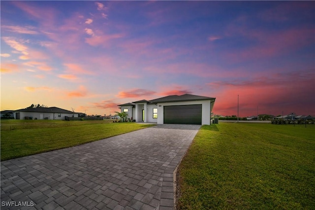 view of front of house with decorative driveway, a front lawn, an attached garage, and stucco siding