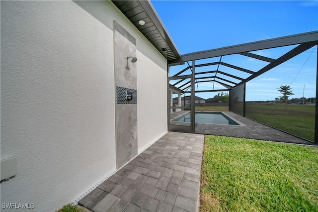 swimming pool with a patio, a lawn, and glass enclosure