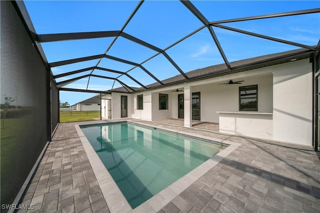 outdoor pool with ceiling fan, a patio, and glass enclosure