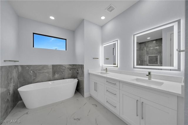 full bath with marble finish floors, double vanity, a freestanding tub, a wainscoted wall, and a shower