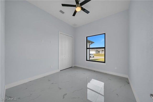 spare room featuring marble finish floors, baseboards, and a ceiling fan