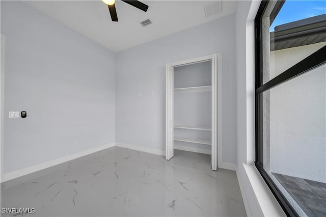 unfurnished bedroom featuring baseboards, marble tiled flooring, ceiling fan, and a closet