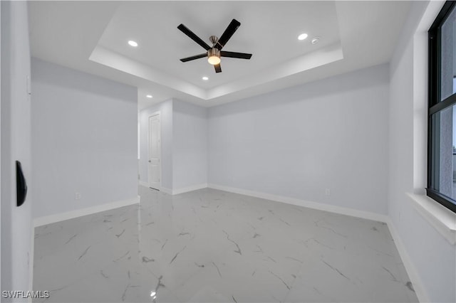 spare room featuring recessed lighting, marble finish flooring, a tray ceiling, baseboards, and ceiling fan