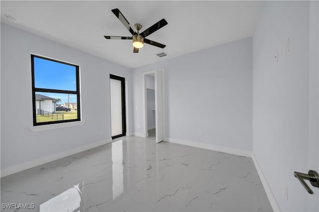 unfurnished room featuring baseboards, light marble finish flooring, and ceiling fan